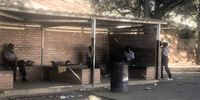 Some members of the police sitting at a shed at the City Hall Car Park in Bulawayo. It's normally a busy place where school children are picked and dropped off, but it was also quiet today. (Photo: Kudzanai Musengi)