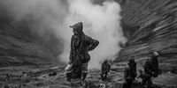 PROBOLINGGO, JAVA, INDONESIA - JULY 18:(EDITOR'S NOTE: Image has been converted to black and white. Color version not available.)   Villagers waits to catch offerings thrown by Tenggerese worshippers during the Yadnya Kasada Festival at crater of Mount Bromo on July 18, 2019 in Probolinggo, Java, Indonesia. Tenggerese people are a Javanese ethnic group in Eastern Java who claimed to be the descendants of the Majapahit princes. Their population of roughly 500,000 is centered in the Bromo Tengger Semeru National Park in eastern Java. The most popular ceremony is the Kasada festival, which makes it the most visited tourist attraction in Indonesia. The festival is the main festival of the Tenggerese people and lasts about a month. On the fourteenth day, the Tenggerese made a journey to Mount Bromo to make offerings of rice, fruits, vegetables, flowers and livestock to throw them into the volcano's caldera. The origin of the festival lies in the 15th century princess named Roro, the principality of Tengger with her husband Joko Seger, and the childless couple asked mountain Gods for help in bearing children. The legend says the Gods granted them 24 children but on the provision that the 25th must be added to the volcano in sacrifice. The 25th child, Kesuma, was finally sacrificed in this initial after refusal, and the tradition of throwing sacrifices into the Caldera to appease the mountain Gods continues today. (Photo by Ulet Ifansasti / Getty Images)
