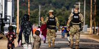 FORT MCCOY, WI - SEPTEMBER 30: U.S. Military Police walk past Afghan refugees at the Village at the Ft. McCoy U.S. Army base on September 30, 2021 in Ft. McCoy, Wisconsin. The Village is the community housing for the Afghans, comprised of eight neighborhoods where the evacuees live, eat, and receive services and support. There are approximately 12,600 Afghan refugees being cared for at the base under Operation Allies Welcome. The Department of Defense, through U.S. Northern Command and U.S. Army North, and in support of the Department of Homeland Security, is providing transportation, temporary housing, medical screening and general support for at least 50,000 Afghan evacuees at suitable facilities in permanent or temporary structures while the Afghans complete the processing necessary to resettle in the United States. (Photo by Barbara Davidson/Getty Images)