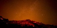 epa09619043 A hill scorched by the Alisal Fire casts an orange glow under the stars in the canyons near Goleta, east of Santa Barbara, California, USA, 13 October 2021. According to the latest reports, the Windy Fire is 13,400 acres with five percent containment.  EPA-EFE/ETIENNE LAURENT