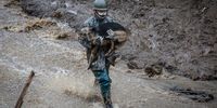 ATAMI, JAPAN - JULY 04: A Japan Self-Defence Force (JSDF) soldier carries a search dog at the site of a landslide on July 04, 2021 in Atami, Shizuoka, Japan. A rescue operation is underway after a landslide, caused by torrential rain, tore through the Japanese resort city of Atami on Saturday, killing two and leaving around twenty missing. (Photo by Yuichi Yamazaki/Getty Images)