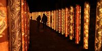 KYOTO, JAPAN - MARCH 15:  Tourists look at the LED lights illuminating the Kimono Forest at Arashiyama, one of Kyoto’s most on March 15, 2021 in Kyoto, Japan. The ‘Kimono Forest’ art installation consists of around 600 textile displays dyed in the traditional Kyo-yuzen style and wrapped around 2 metre-high cylinders lining a route from Randen tram station on Kyoto’s Keifuku Arashiyama line. (Photo by Buddhika Weerasinghe/Getty Images)