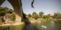 A Kosovar high diver plunges from the 18m platform during the acrobatic jump competition at the Fshajt bridge on 1 August 2021 in the municipality of Gjakova, Kosovo. (Photo: Ferdi Limani / Getty Images)