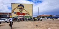 The group stops for a photo in front of Boniswa, the giant mural outside the Isivivana Centre in Khayelitsha. (Photo: Shaun Doch)