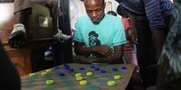 Prince Raymond, from Congo, plays an intense game of draft inside the Central Methodist Church at Greenmarket Square. He is one of close to 600 displaced migrants seeking refuge at the church which has been deemed unsafe following violent altercations. 8 January 2020. Photo: Sandisiwe Shoba<br>