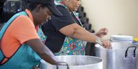 Shirley Grootboom and Yvonne Ncapay, two of the three cooks at The Crags Primary School, dish up food for the learners. (Photo: Daily Maverick file photo)