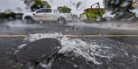 A storm water pipe overflows into Frans Conradie Drive as a motorist passes by on June 13, 2022 in Cape Town, South Africa. It is reported that the South African Weather Services (SAWS) has issued a warning for possible flooding due to the heavy rainfall. (Photo by Gallo Images/Die Burger/Jaco Marais)