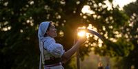 A woman in a tratidional working outfit, whets her scythe in the early morning in Stromovka park, in the city center in Prague, Czech Republic, 02 June 2023. About thirty locals gathered to scythe flower meadow in the biggest Prague's city park.  EPA-EFE/MARTIN DIVISEK