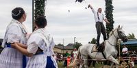 A participant on a horse plucks the head of a dead cock hanging from a frame during a cock plucking competition in the village of Heinersbrueck, Germany 12 August 2023. The Sorbian people of Heinersbrueck held their traditional harvest festival. Among a parade through their village, one of the highlights is the traditional cock plucking competition. Young men on horses try to grab and remove the head from the body of an already dead cock, that hangs from a decorated frame. The Western Slavic people of the Sorbs are acknowledged as a national minority with their own language in eastern Germany.  EPA-EFE/CLEMENS BILAN