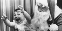 23rd December 1969:  A baby screams in the arms of a traditional English Santa Claus.  (Photo by Keystone/Getty Images)
