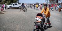 A man returns home with his food parcel in a pram. (Photo: Donna van der Watt)