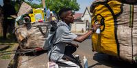 BRIXTON, SOUTH AFRICA - SEPTEMBER 28: Local artist Tumi Thagoli (28) sprays the bag of a reclaimer during a breakfast with local reclaimers.  They joined artists and other interested people for a breakfast at Shade on September 29, 2021 in Brixton., South Africa.  They also had their bags sprayed by local artists as part of the Waste Not Want Not Project. The Waste Not Want Not Art/Recycle Project is supported by Goethe-Institute and British Council and  is an art project where different artists have access to materials sourced from reclaimers in the Brixton area by Shade.    (Photo by Gallo Images/Alet Pretorius)