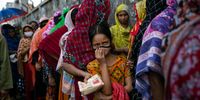DHAKA, BANGLADESH - JULY 6: People queue for discounted food given out by a government program July 6, 2021 in Dhaka, Bangladesh. Bangladesh enacted a nationwide lockdown on July 1st in an effort to contain a third wave of coronavirus as cases have surged, fueled by the Delta variant first detected in neighboring India.  (Photo by Allison Joyce/Getty Images)