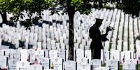 WASHINGTON, DC - MAY 31: A U.S. soldier stands with a bouquet of flowers amongst the headstones of those killed during the wars in Iraq and Afghanistan in Section 60 of Arlington National Cemetery during Memorial Day on May 31, 2021 in Arlington, Virginia. (Photo by Samuel Corum/Getty Images)
