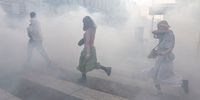 PARIS, FRANCE - APRIL 14: Passers-by run through clouds of tear gas as students demonstrate in rejection of the two final candidates in the French presidential election - incumbent Emmanuel Macron and far-right candidate Marine Le Pen on April 14, 2022, in Paris, France. Students have barricaded themselves inside the Sorbonne campus and, for now, are refusing to leave. (Photo by Sam Tarling/Getty Images)