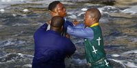 A church member of the uKukhanya kuka Jehova Church in Mngadi Katlehong  spits out water after being dipped in the Klip RIver. Photo: Felix Dlangamandla