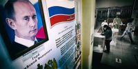 A woman votes on 1 July 2020, the main day of a nationwide vote on amendments to the Russian constitution, next to a portrait of Russian President Vladimir Putin at a polling station in Moscow. (Photo: EPA-EFE / Maxim Shipenkov)