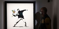 LONDON, ENGLAND - MAY 18: An visitor views one of the works on display during the "The Art of Banksy" press call at Covent Garden on May 18, 2021 in London, England.  The exhibition brings together works and prints from many private collectors.  (Photo by Tim P. Whitby/Getty Images)