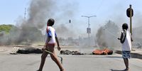 Youths walk past burning barricades during a protest in Maputo, Mozambique on 4 December. (Photo: Luisas Nhantumbo / EPA-EFE)