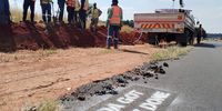 Construction workers stand near a spray-painted pothole. (Photo: Supplied)