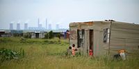 Children play outside a shack in Mooidraai with the Lethabo power plant in the distance. The industries that make people ill are seen by many in the community as the only source of jobs in the region. Photographer: Leon Sadiki/Bloomberg