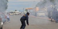 A police officer uses a stun grenade against EFF supporters during a protest in the Mthatha CBD. (Photo: Hoseya Jubase)