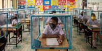Thai students wear face masks and sit at desks with plastic screens used for social distancing at the Wat Khlong Toey School on August 10, 2020 in Bangkok, Thailand. In the beginning of July The Wat Khlong Toey School reopened its doors to its approximately 250 students following the relaxation of lockdown measures during the COVID-19 pandemic. When the school was forced to shutter its doors in mid March due to Thailand's emergency decree and lockdown, the administration and teachers prepared measures to ensure a safe reopening. By installing sinks and soap dispensers outside of each classroom, creating social distancing screens in classrooms and lunch areas and installing hand sanitizer and temperature scanners at the entry the Wat Khlong Toey school has been open for a month and has had zero cases of COVID-19. Although Thailand is now allowing schools throughout the country to further relax safety measures, the Wat Khlong Toey school has chosen to continue strict social distancing to ensure the safety of their students and teachers. (Photo by Lauren DeCicca/Getty Images)