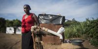 Nokthula Mbaso stands beside a communal tap as she washes her clothing. (Photo: Shiraaz Mohamed)