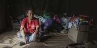 Karen Andrews surrounded by clothing donated to herself and family in a tent that now serves as her new home.<br>Photo / Shiraaz Mohamed