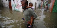 A man carries a child as he walks through a flooded area after heavy monsoon rains in Karachi, Pakistan, 11 August 2019. EPA-EFE/SHAHZAIB AKBER