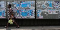A woman walks past election posters bearing the portrait photos of Nigeria's President-elect Bola Ahmed Tinubu in Abule Egba district of Lagos, Nigeria on 1 March 2023. (Photo: EPA-EFE / Akintunde Akinleye)