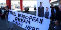 Activists hold a banner depicting Italian Prime Minister Giorgia Meloni and Albanian Prime Minister Edi Rama wearing police uniforms, as the first group of migrants intercepted in Italian waters arrive aboard an Italian navy boat at Shengjin, Albania, 16 October 2024. Italy has begun sending migrants rescued in the Mediterranean to detention centers in Albania, where their asylum claims will be processed. The plan, finalized in February 2024, allows Italy to transfer up to 36,000 asylum seekers to Albania annually, with the goal of deterring migrants from attempting to reach Italy. While the Italian government and some EU leaders support the program, human rights groups criticize it for potentially putting migrants at risk and exposing them to rights violations.  EPA-EFE/MALTON DIBRA