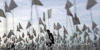 LOS ANGELES, CALIFORNIA - NOVEMBER 18: A person wearing a face covering walks past a white flag memorial installation outside Griffith Observatory honoring the nearly 27,000 Los Angeles County residents who have died from COVID-19 on November 18, 2021 in Los Angeles, California. Los Angeles is holding a three-day citywide ‘Strength and Love’ memorial honoring those who died and those who ‘have held the city together throughout the pandemic’ including first responders and essential workers. Los Angeles County reported 26 additional deaths due to COVID-19 today. (Photo by Mario Tama/Getty Images)