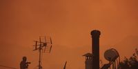 A man sprays water from the rooftop of his house during a wildfire at Lagonisi area in Attica, Greece, 17 July 2023. Firefighting forces are battling a blaze that broke out in the Kouvaras area in Attica, while a warning was sent via the emergency number 112 to evacuate several settlements in southeast Attica. A force of 55 firefighters and 20 fire engines, two units on foot and 31 Romanian firefighters with five water tankers have been deployed to put out the fire, assisted by six fire-fighting aircraft and four helicopters from the air. EPA-EFE/KOSTAS TSIRONIS