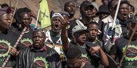 Mineworkers wearing Amcu T shirts sit on the koppie before the ceremony. Many have questioned why 16 August has not been declared a public holiday in commemoration of the killed miners. (Photo: Shiraaz Mohamed)