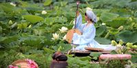 A woman poses for a photo next to lotus flowers in West lake in Hanoi, Vietnam, 09 June 2025.. Lotus flowers bloom from late May to August in Vietnam and are commonly found growing in the muddy waters of lakes and ponds across the country.  EPA-EFE/LUONG THAI LINH