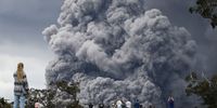 HAWAII VOLCANOES NATIONAL PARK, HI - MAY 15:  People watch at a golf course as an ash plume rises in the distance from the Kilauea volcano on Hawaii's Big Island on May 15, 2018 in Hawaii Volcanoes National Park, Hawaii. The U.S. Geological Survey said a recent lowering of the lava lake at the volcano's Halemaumau crater 'has raised the potential for explosive eruptions' at the volcano.  (Photo by Mario Tama/Getty Images)