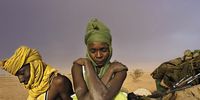 Soldiers with the Sudanese People’s Liberation Army sit by their truck, waiting<br>for it to be repaired, as a sandstorm approaches in Darfur, Sudan. August 2004. (Photo: Courtesy of Lynsey Addario and Lyles & King, New York)