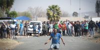 A man gestures at law enforcement officials (not pictured) in Eldorado Park, Johannesburg on 27 August 2020. Residents protested the killing of a local teenager. (Photo: Shiraaz Mohamed)