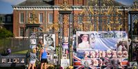 LONDON, ENGLAND - AUGUST 31: Two people stop to look at the messages and photographs outside Kensington Palace as fans of Princess Diana gather to show their support on August 31, 2022 in London, England. Diana, Princess of Wales died on the night of August 31, 1997, when the car she was travelling in collided with the Pont de l'Alma tunnel in Paris, France. She was travelling with her partner Dodi Fayed who also died, as did the driver of the Mercedes Henri Paul.  (Photo by Leon Neal/Getty Images)