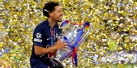 Marquinhos of Paris Saint-Germain carries the UEFA Champions League trophy to the winners stage as he celebrates after his team's victory, to secure Paris Saint-Germain's first ever UEFA Champions League title in the club's history and a record UEFA Champions League Final winning scoreline of 5-0, following the UEFA Champions League Final 2025 between Paris Saint-Germain and FC Internazionale Milano at Munich Football Arena on May 31, 2025 in Munich, Germany. (Photo by Carl Recine/Getty Images)