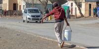 A resident carries water home from the Gift of The Givers truck. (Photo: James Fowler)