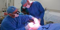 Dr Nick Kairinos, left) a plastic and reconstructive surgeon at the Netcare Christiaan Barnard Hospital in Cape Town, uses an electric scalpel to remove skin around the bedsore. Dr Alex Landau assists. (Photo: Elsabé Brits)