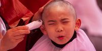 A young monk reacts as he gets his hair shaved off during the 'Children becoming Buddhist monks' ceremony at the Jogyesa temple in Seoul, South Korea, 09 May 2023. The children will stay at the temple to learn about Buddhism for 21 days. South Korean Buddhists prepare to celebrate Buddha's upcoming birthday on 27 May.  EPA-EFE/JEON HEON-KYUN