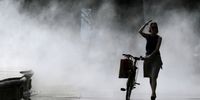 A woman gets cooled off while passing a water mist during a hot summer day in Bucharest, Romania, 24 July 2023. Meteorologists are forecasting above-normal temperatures in Romania's capital and southern regions for the next two days. Bucharest is being announced for tomorrow with the red code alert because of air temperatures above 40 Celsius degrees in the shade.  EPA-EFE/Robert Ghement