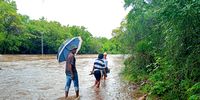 Residents of GaMampa in the Sekhukhune district of Limpopo wade through the flooded Mohlapitsi river after returning from registering children at a primary school in neighbouring Mafefe village. The flooded river has cut off all transport connecting the two villages, rendering children unable to attend classes on the opening of the 2026 academic year. (Photo: Lucas Ledwaba / Mukurukuru Media)