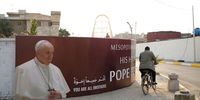 BAGHDAD, IRAQ - MARCH 03: A man cycles past a poster of Pope Francis outside Catholics cathedral of our lady of salvation ahead of the planned visit of Pope Francis on March 3, 2021 in Baghdad, Iraq. On March 5, Pope Francis will start the historic first ever papal visit to Iraq. In his first foreign trip since the start of the pandemic Pope Francis will visit Baghdad, Najaf, Erbil and the cities of Qaraqosh and Mosul, which were heavily destroyed by ISIS. Although the trip is seen as an act of solidarity, the Vatican has been forced to defend the decision to go ahead with the papal visit amid the ongoing coronavirus pandemic, as Iraq is currently seeing a spike in infection rates as it faces a deadly second wave of the virus. (Photo by Taha Hussein Ali/Getty Images)
