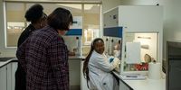 Minister Barbara Creecy watching PhD student Katlego Matlou (right) preparing a mixture of reagents used to amplify DNA in a process called Polymerase Chain Reaction. (Photo: Julia Evans)