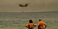 PATRAS, GREECE - AUGUST 01: Local residents watch as a Greek army Chinook helicopter collects water as firefighters continue to tackle a wildfire near the village of Lambiri on August 1, 2021 in Lambiri, Greece. Nearly 300 firefighters, two water bomber planes and five helicopters were battling to put out a forest fire in Greece that has so far destroyed around 20 homes and injured eight people, authorities said. (Photo by Milos Bicanski/Getty Images)