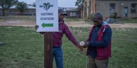 An official from the Lesotho Independent Electoral Commission hangs a poster indicating the direction to the St. Joseph Primary school in Koro-Koro, on October 7, 2022 where voting operations for the parliamentary elections are about to start. Voters in the southern African kingdom of Lesotho cast their ballots on October 7, 2022.<br>Photo: Shiraaz Mohamed.